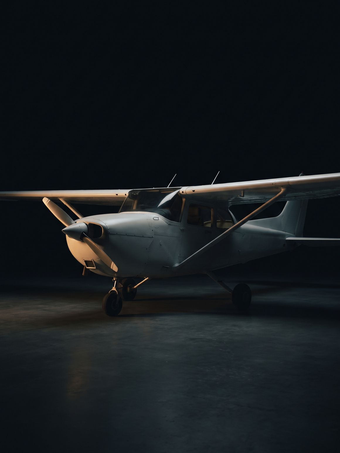 The Cessna 172 the course is flown in, parked in a dark hangar under a single cold light